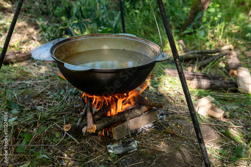 Cauldron on the fire. Cooking food on a campfire in a wild campsite on a summer day.