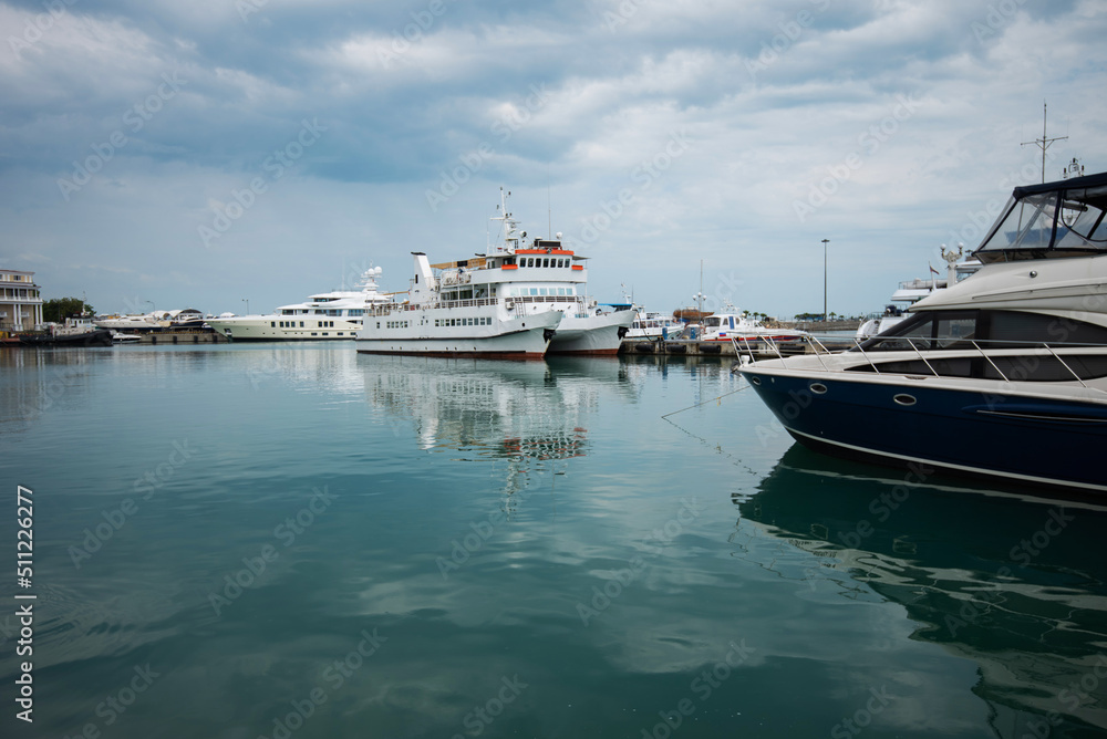 Luxury yachts docked in sea port. Marine parking of modern motor boats and azure water. Tranquility, relaxation and fashionable vacation. White yachts and sailboats moored in marina, summer season.