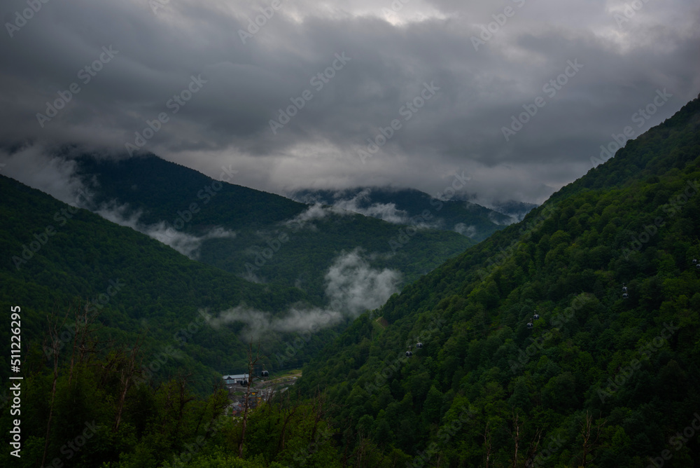 Spring morning at mountains and clouds. Atmospheric landscape with trees and low clouds on cloudy sky. Awesome mountain scenery.