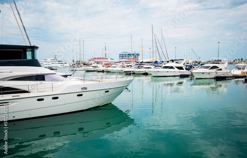 Luxury yachts docked in sea port. Marine parking of modern motor boats and azure water. Tranquility, relaxation and fashionable vacation. White yachts and sailboats moored in marina, summer season. © eskstock