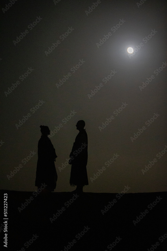 Buddhist monks standing under the moonlight during a zen retreat in the Sahara, Morocco. 25.02.2017