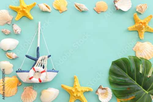 nautical concept with sail boat, star fish and seashells over mint blue wooden background photo