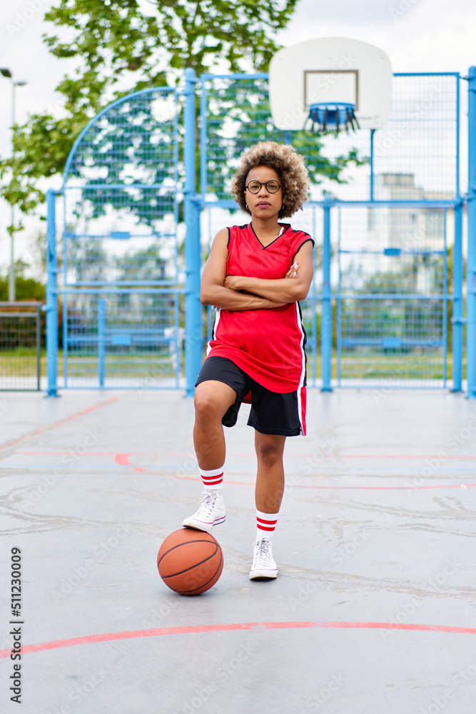 girl with afro hairstyle with a ball on a basketball court