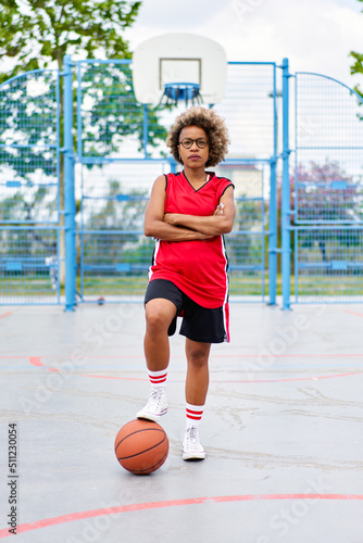 girl with afro hairstyle with a ball on a basketball court © JENOCHE