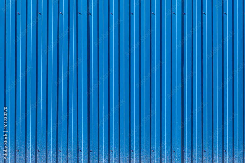 Fence made of blue profiled sheeting with mud splashes in the lower part Fence made of blue profiled sheeting with mud splashes in the lower part
