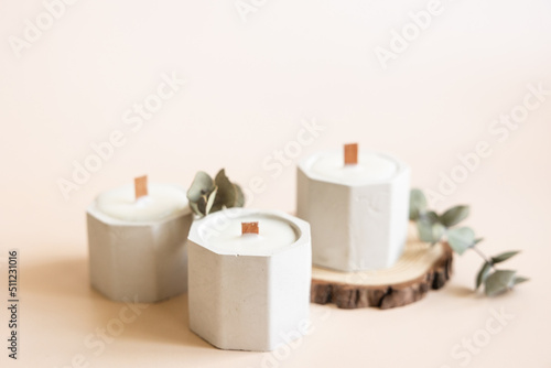 Handmade candles from paraffin and soy wax in concrete plaster candlestick with wooden wick and dry herbal isolated on pastel beige background. Copy space