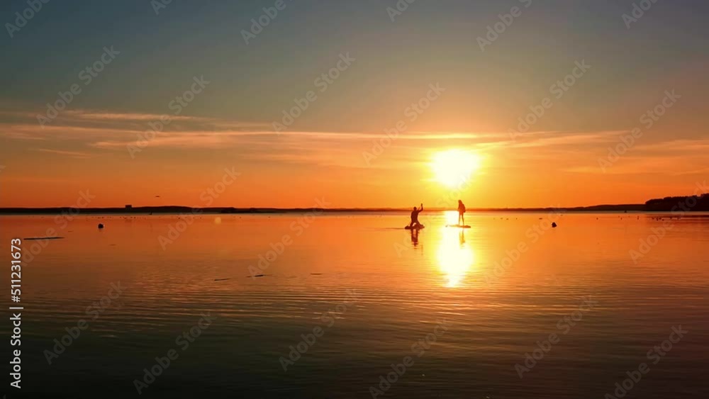 People start surf on stand up paddle boarding. Sup board evening relax. Warm summer time beach vacation holiday. Journey. Young man and girl relaxing surf swimming. Water sport floating on sunset. People start surf on stand up paddle boarding. Sup board evening relax. Warm summer time beach vacation holiday. Journey. Young man and girl relaxing surf swimming. Water sport floating on sunset.