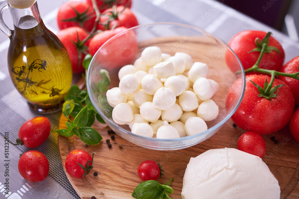 Ingredients for Caprese salad - Mini mozzarella cheese in glass bowl, tomato and basil Ingredients for Caprese salad - Mini mozzarella cheese in glass bowl, tomato and basil