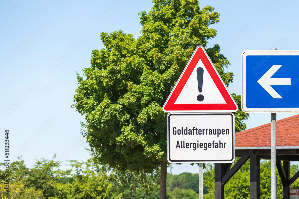 Warnschild vor Goldafterraupen und Allergiegefahr auf einem Autobahnparkplatz