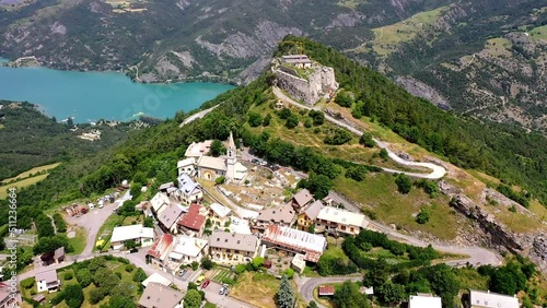 Flug über Bergwelt um die Kirche Saint Vincent Les Forts mit Blick auf den Stausee Ubaye Valley, Lac de SerrePoncon, Saint Vincent les Forts, Alpes-de-Haute-Provence, Frankreich photo