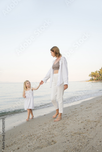 Mother and daughter walking on the beach. Family summer vacation concept. 