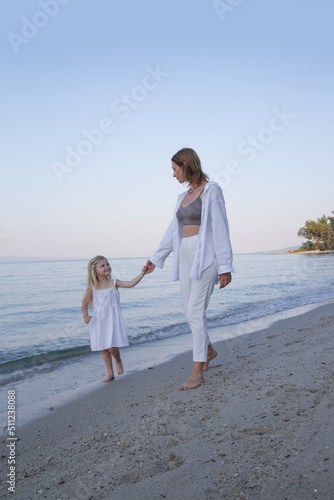 Mother and daughter walking on the beach. Family summer vacation concept. 