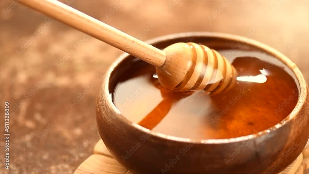 Honey dripping, pouring from honey dipper in wooden bowl. Close-up. Healthy organic fresh thick honey dipping from the wooden honey spoon, closeup. 4K UHD video footage. Slow motion. Honey dripping, pouring from honey dipper in wooden bowl. Close-up. Healthy organic fresh thick honey dipping from the wooden honey spoon, closeup. 4K UHD video footage. Slow motion.