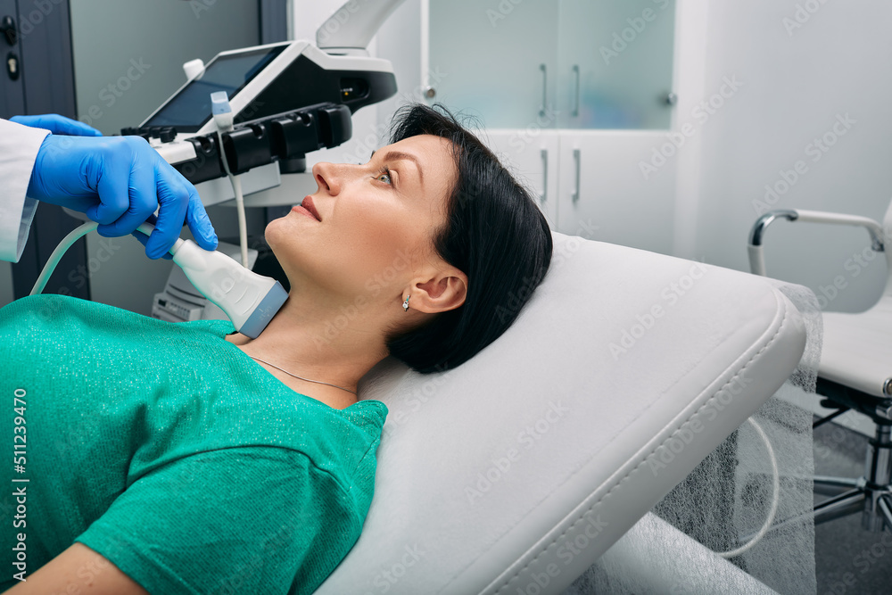 Endocrinology and ultrasound of thyroid gland. Exam endocrine system of woman patient at hospital with ultrasound machine Endocrinology and ultrasound of thyroid gland. Exam endocrine system of woman patient at hospital with ultrasound machine