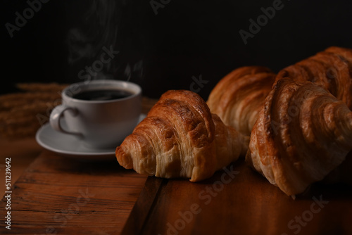 Tasty croissants and hot coffee on wooden wooden board ready to serve for breakfast. Breakfast, bread bakery products cafe concept