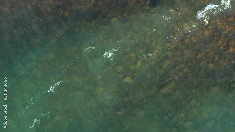 A dynamic aerial shot above the Lake Superior in Minnesota while facing downwards towards the water. It's a top-view footage of the crystal clean waters with waves, shadows and visible seabed. A dynamic aerial shot above the Lake Superior in Minnesota while facing downwards towards the water. It's a top-view footage of the crystal clean waters with waves, shadows and visible seabed.