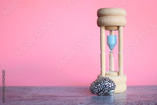 Brain model and sandglass on table with pink background. Time to think, time management concept