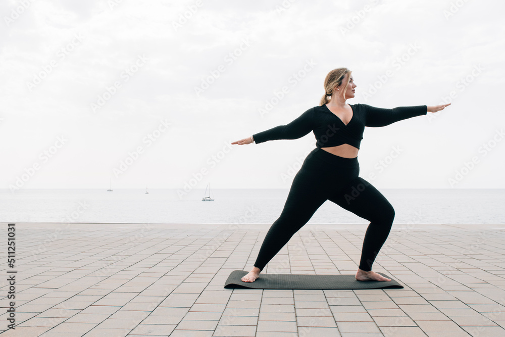 plus size girl practicing yoga in front of the ocean plus size girl practicing yoga in front of the ocean