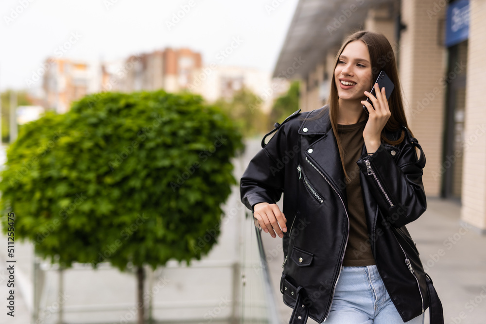 Young woman walking outdoors, talking on mobile phone Young woman walking outdoors, talking on mobile phone