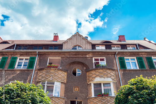 A beautiful tenement house at Plac Staromiejski in Nysa. A view of a pre-war tenement house. White window frames and green shutters. Red tile on the roof. A beautiful sunny day with deep blue skies photo