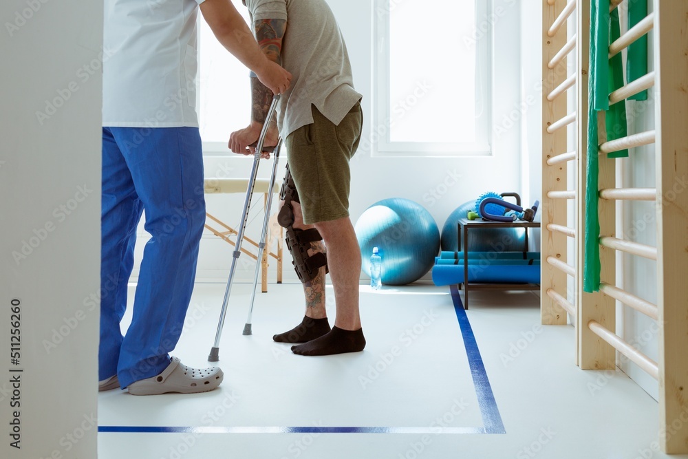 Fototapeta premium Injured patient learns to walk on crutches in medical office