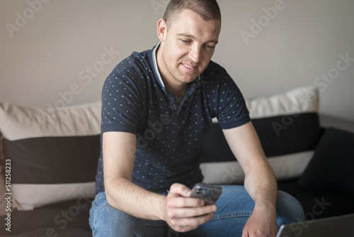 06.09.2022 - Pleven,Bulgaria - Happy young man social networking and texting with his smart phone at home