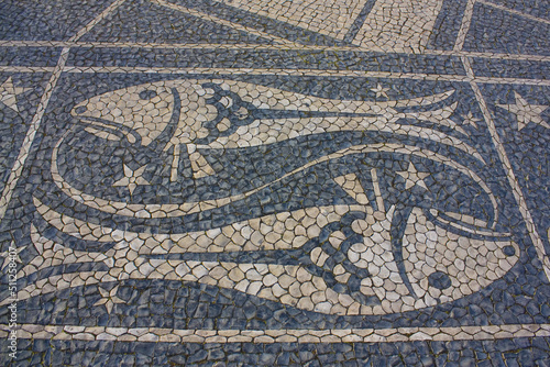 Traditional pattern cobblestone pavement (calçada portuguesa) with image of fish zodiac sign in Belem, Lisbon, Portugal