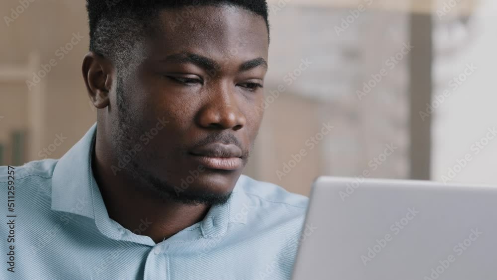 Confident african businessman young american ethnic guy work online use personal computer wi-fi connection concentrated focusing on distance internet job e-business typing email close up male portrait Confident african businessman young american ethnic guy work online use personal computer wi-fi connection concentrated focusing on distance internet job e-business typing email close up male portrait