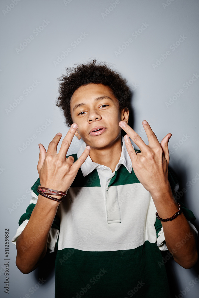 Vertical portrait of black teenage boy looking at camera and gesturing shot with flash Vertical portrait of black teenage boy looking at camera and gesturing shot with flash