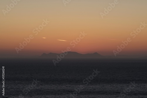 View of the sun slowly setting behind the volcano of Santorini and producing a spectacular sunset