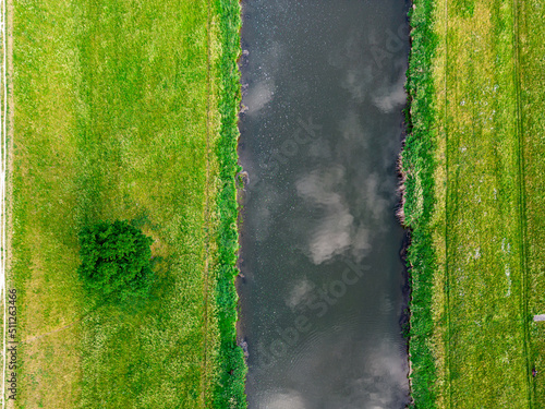 równoległe linie brzegowe kanału lub rzeki z trawnikiem i drzewem widziane z góry photo