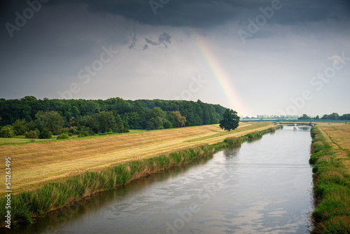 tęcza po deszczu nad lasem na brzegu kanału lub rzeki © Henryk Niestrój