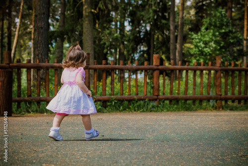 little 2 year old girl in a park near a forest
