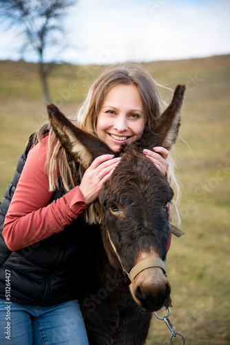 beautiful blonde girl hugging donkey in the autumn field