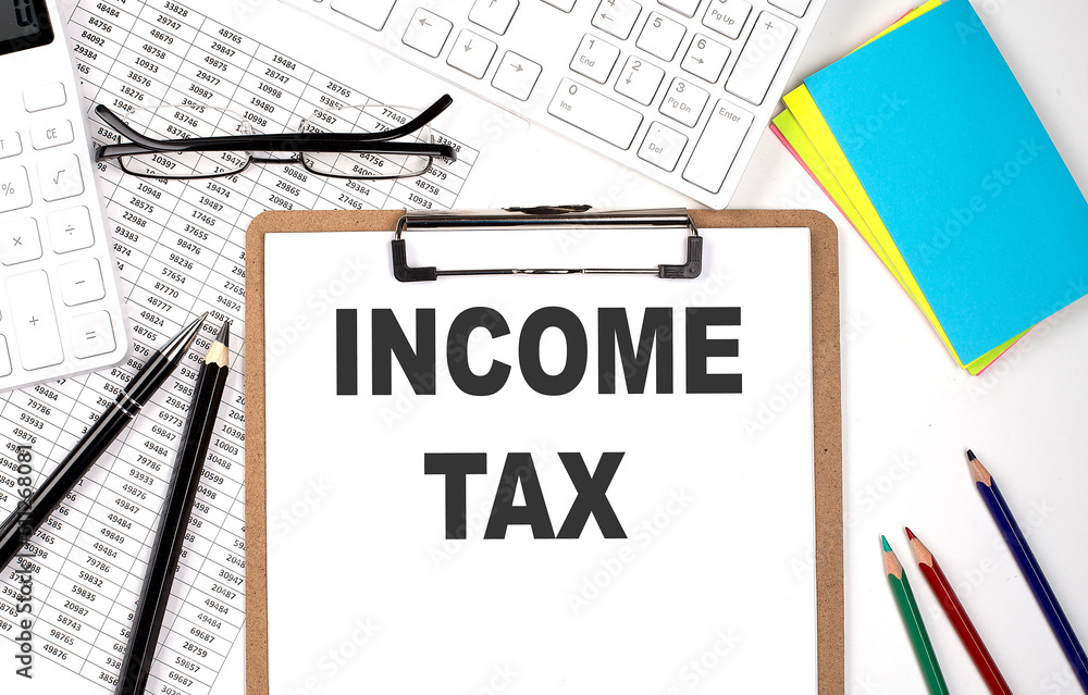Clipboard with text INCOME TAX and keyboard and chart on white background. Clipboard with text INCOME TAX and keyboard and chart on white background.