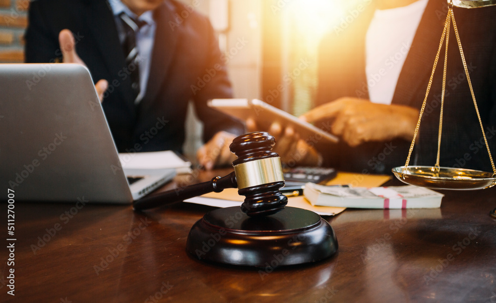 Justice and law concept.Male judge in a courtroom with the gavel, working with, computer and docking keyboard, eyeglasses, on table in morning light Justice and law concept.Male judge in a courtroom with the gavel, working with, computer and docking keyboard, eyeglasses, on table in morning light