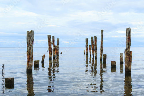 Sea scenery with broken pier poles sticking from water.