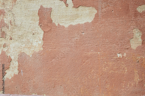 The outer surface of the wall of an old building. Abstract background. The texture of the dilapidated multilayer building material in red.