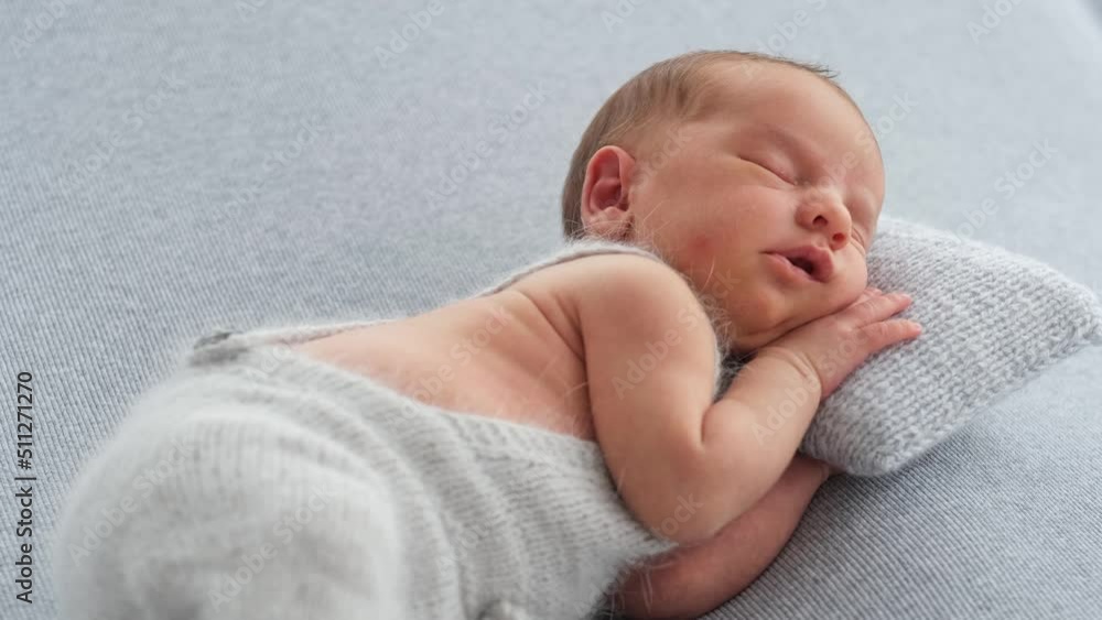 Newborn baby boy sleeping on knitted pillow and holding his hand under his head Newborn baby boy sleeping on knitted pillow and holding his hand under his head