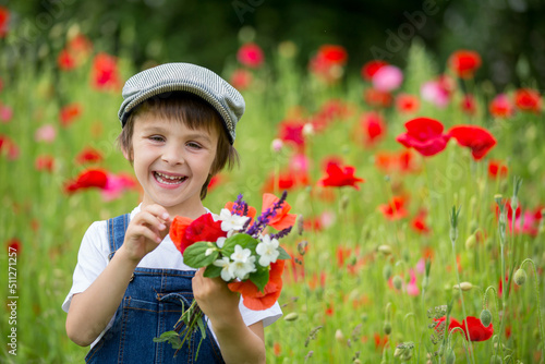 Cute preschool child in poppy field  holding a bouquet of wild flowers