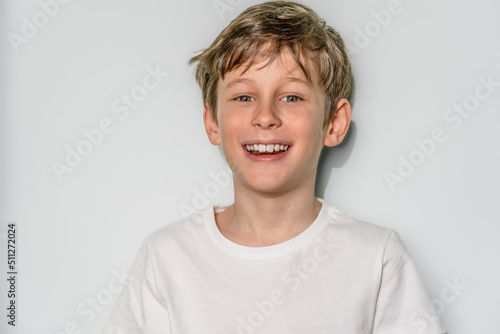 Portrait of a laughing white Eastern European 9 year old boy wearing a white t-shirt. The child looks directly into the camera with a smile. copy space on the left