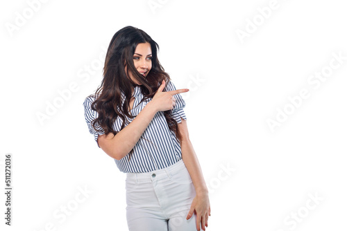 Beautiful smiling happy brunnet сaucasian young girl in white pants and striped shirt pointing right with her finger isolated on white background photo