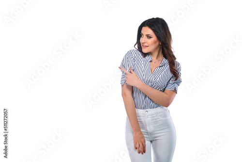 Beautiful smiling happy brunnet сaucasian young girl in white pants and striped shirt pointing left with her finger isolated on white background photo