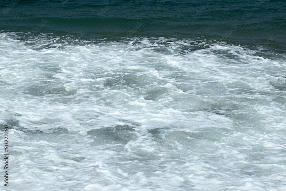 Natural wavy background of blue bubbling sea water.