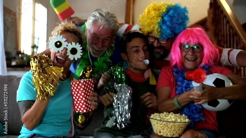 Group of friends supporters excited exult during a football match on tv. Family people watching world cup on television and have fun together exulting for the score. Mixed ages and sport channel