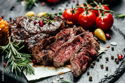 Sliced steak ribeye, grilled on a dark stone background. Restaurant menu, dieting, cookbook recipe top view