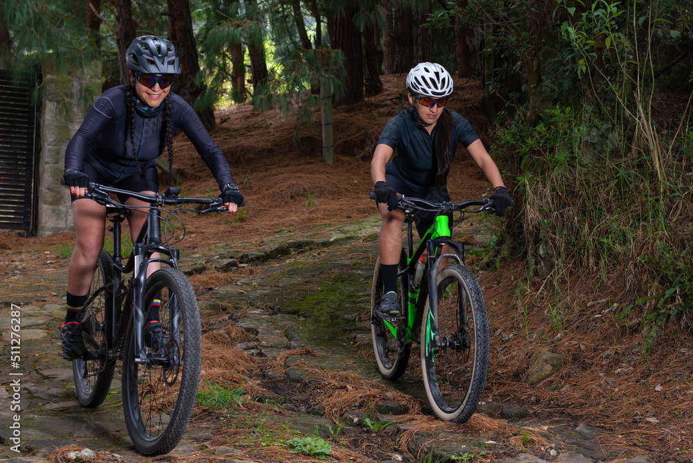 Obraz premium Two female cyclists riding their bikes down a mountain