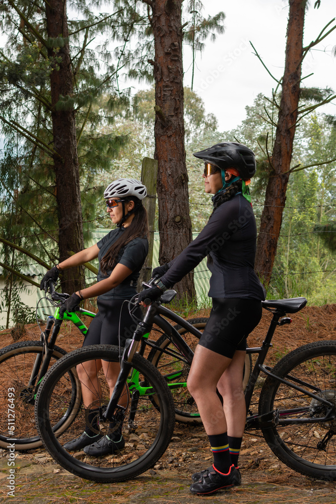 Female cyclists standing holding their bikes in the middle of the forest. Selective focus