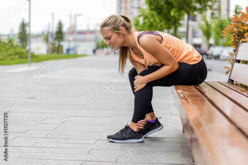 Running injury leg accident- sport woman runner hurting holding painful sprained ankle in pain. Athlete woman has ankle injury, sprained ankle during running training. Space for text
