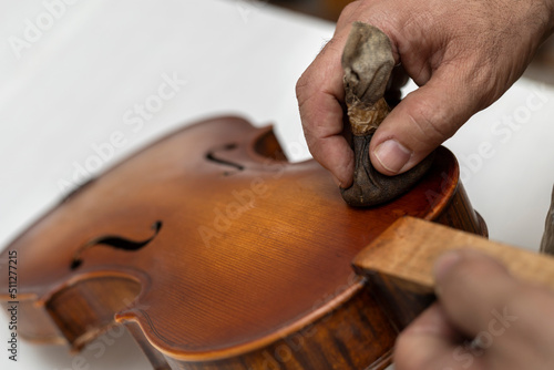 Fotografie Close-up of unrecognizable Latin American Luthier varnishes a violin the old fashioned way using natural dyes